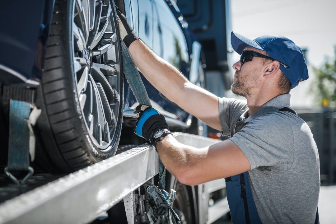 towing-truck-driver-securing-transported-vehicle Jump-start services